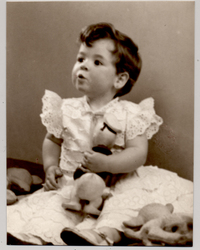 [Niñita de pelo ondulado, partidura al lado, vestido de broderí blanco con vuelos, mejillas rosadas, con un juguete en sus manos y en distintas posiciones]