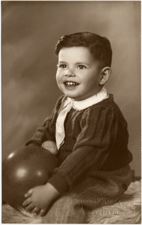 [Dos hermanitos sonrientes posando uno al lado del otro y uno de ellos posando sentado en un felpudo con una pelota en la mano]