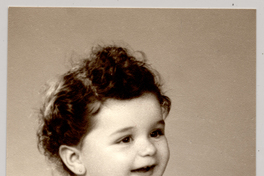 [Niñita regordeta de pelo ruliento en calzones con una medalla en el cuello y sentada sobre un felpudo en distintas poses]