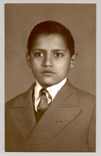 [Niño moreno de chaqueta oscura con solapa ancha]