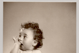 [Niñita de aproximadamente dos años posando con un vestido blanco con los brazos desnudos y un dedo en la boca]