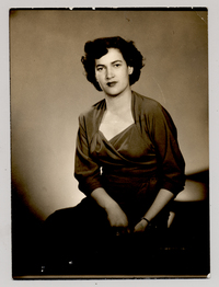 [Mujer morena de pelo ondulado y vestido oscuro posando sentada]