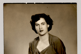 [Mujer morena de pelo ondulado y vestido oscuro posando sentada]