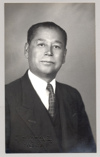 [Hombre de rasgos algo asiático traje oscuro y corbata a rayas]