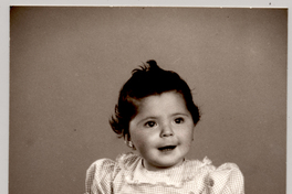 [Niñita sentada sobre un felpudo con vestido a cuadrillé y descalza]