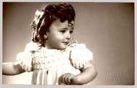 [Niñita de pelo rizado, vestido blanco con mangas englobadas]