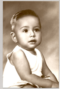 [Bebé moreno de pelo corto con una polera blanca sin mangas]