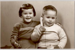 [Una niña y un niño, [hermanos], ella con una pelota y él con un teléfono, ambos sonrientes]