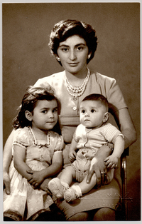 [Madre sentada con sus dos hijos, una niña y un bebé]