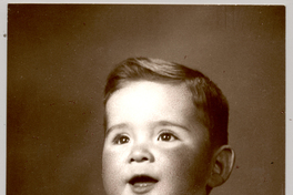 [Bebé rubio cara rosasea polera blanca sin mangas con un juguete en sus manos y sonriendo]