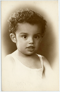 [Niñita de tez morena, pelo corto y crespo con una camiseta blanca y otra hablando por teléfono]