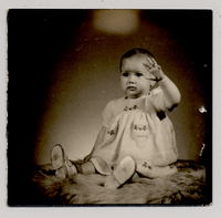 [Guagua rubia sentada sobre un felpudo con su brazo izquierdo arriba]