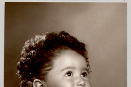 [Niñita de pelo rizado peinado hacia atrás vestido blanco mangas cortas y una cadena colgando en el cuello]