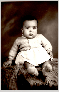 [Guaguita de vestido chaleco y zapatos de lana sentada sobre un felpudo]