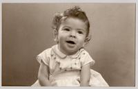 [Niñita de pelo rubio risado, vestido blanco bordado en la pechera y amarrado en la cintura]