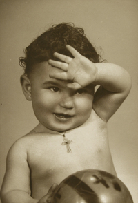 [Niñita desnuda con una pelota en su mano derecha y una cadena con un cristo colgando en el cuello]