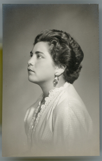 [Joven mujer morena de cara regordeta peinada hacia atrás, con aros grandes, blusa clara con bordados en las orillas, posando de perfil]