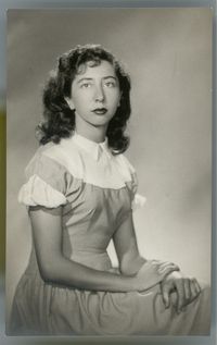 [Mujer joven posando sentada con un vestido de pechera blanca y mangas cortas con vuelos]