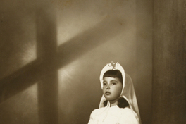 [Niña de Primera Comunióncon una amplia toca amarrada bajo el cuello y velo largo]