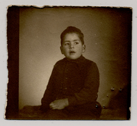 [Niño regordete y tes morena con chaleco oscuro posando sentado]