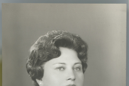 [Mujer adulta de pelo corto, regordeta, tez y ojos claro, abrigo oscuro bordado en la solapa, aros y collar de perlas blancas]