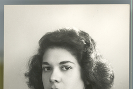 [Mujer joven de tez morena, pelo ondulado, vestido camisero a cuadros, posando de medio cuerpo y de lado]