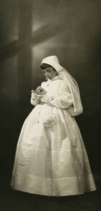 [Niña de Primera Comunión con guantes blancos y una toca con velo hata la cintura]