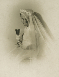 [Niña de Primera Comunión observando el caliz que tiene entre sus manos]