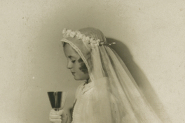 [Niña de Primera Comunión observando el caliz que tiene entre sus manos]