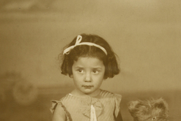 [Niñita sentada en un baúl con un osito de peluche]