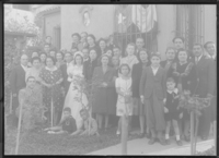 [Novios posando con un gran número de familiares y amigos en el jardín de la casa]