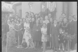 [Novios posando con un gran número de familiares y amigos en el jardín de la casa]