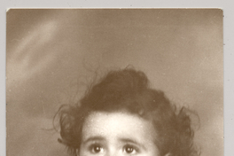 [Niñita de vestido blanco con vuelos pelo crespo ojos grandes y un dedo metido en la boca]