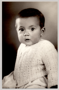 [Guagua morena de pelo corto con chaleco de lana blanca, vestido blanco y aros]