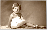 [Niñita rubia sentada de lado con las piernas cruzadas, vestido de dos colores y chalas blancas]