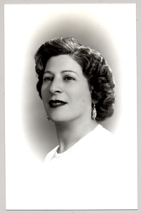 [Mujer joven de pelo ondulado peinado hacia atrás con aretes largos y labios rojos]