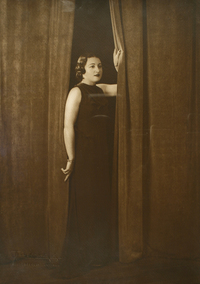 [Mujer joven y regordeta de pie con un vestido largo posando afirmada entre dos cortinas]