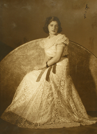 [Mujer joven de vestido de broderí color blanco largo con una cinta roja en la cintura]