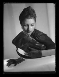 [Mujer vestida de negro con turbante, cartera y guantes]