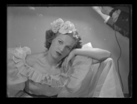 [Mujer con flores en el pelo, apoyando su mejilla en la mano]