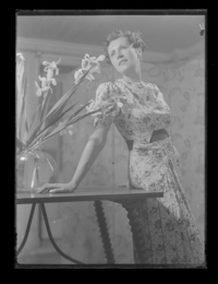 [Mujer de pie junto a un florero]