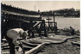Con azuela dan distintas formas a los maderos que componen el esqueleto de los lanchones. Aquí preparan el deslizadero de un lanchón que empezarán a construir