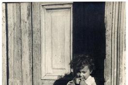 [Niñita de pies descalzos, sentada sobre el umbral de la puerta de su casa en Pomaire]