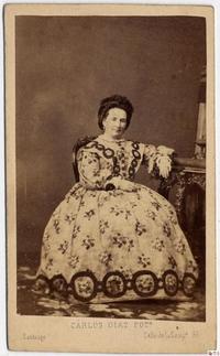 [Dama sentada, apoya su brazo sobre una mesa]