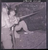 [Mineros trabajando con taladro en galería subterránea de la mina]