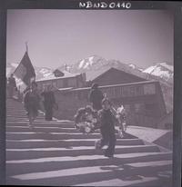 [Dos hombres llevando un pendón y niños con una corona de flores]