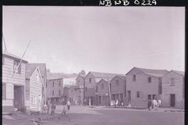 [Personas reunidas en las puertas de sus casas en una calle de pueblo]