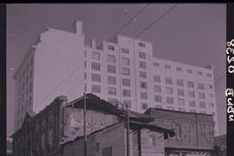 [Transeúntes por una calle con casas antiguas en demolición contiguo a edificio de departamentos]