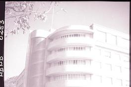 [Autos estacionados en el frontis de un edificio, atrás se divisa un cerro]