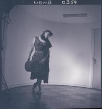 [Bailarina de ballet, caracterizada para una obra, posando de pié en una posición de movimiento]